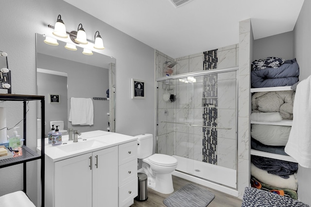 bathroom featuring an enclosed shower, vanity, wood-type flooring, and toilet