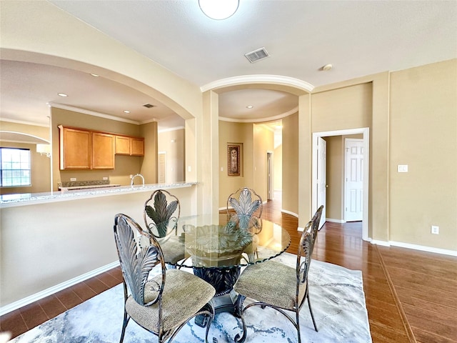 dining room featuring dark hardwood / wood-style flooring, ornamental molding, and sink