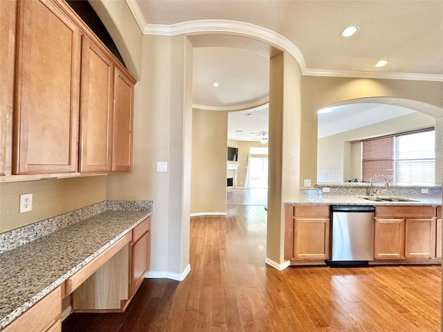 kitchen featuring light stone counters, sink, stainless steel dishwasher, and light hardwood / wood-style floors