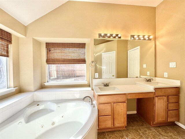 bathroom featuring tile patterned flooring, a bath, vanity, and lofted ceiling