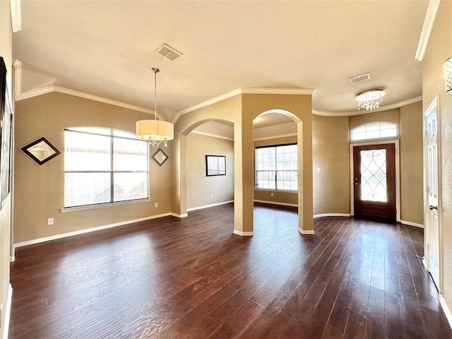 entryway with ornamental molding, dark wood-type flooring, and a notable chandelier