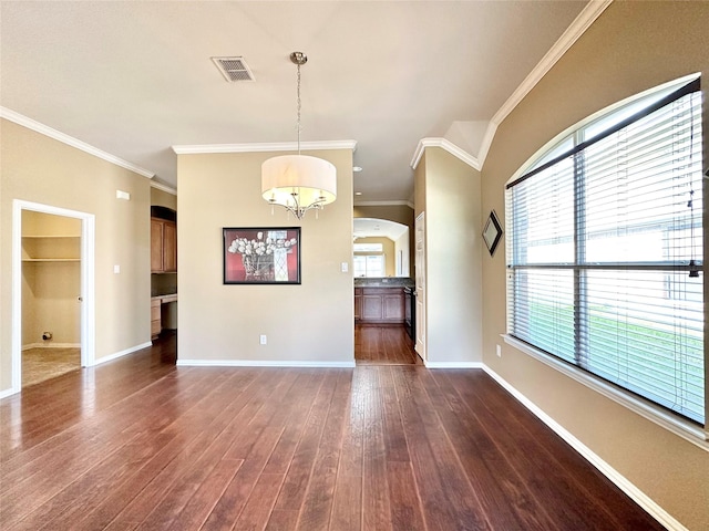 empty room featuring a notable chandelier, dark hardwood / wood-style floors, and crown molding