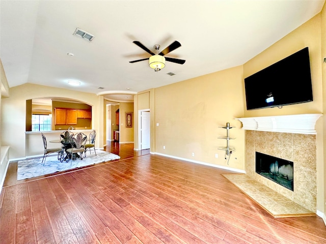 unfurnished living room featuring ceiling fan, a fireplace, lofted ceiling, and hardwood / wood-style flooring