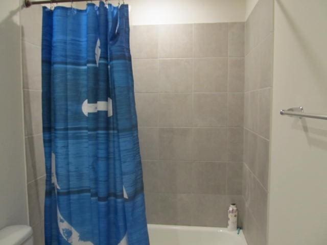 bathroom with shower / tub combo and toilet