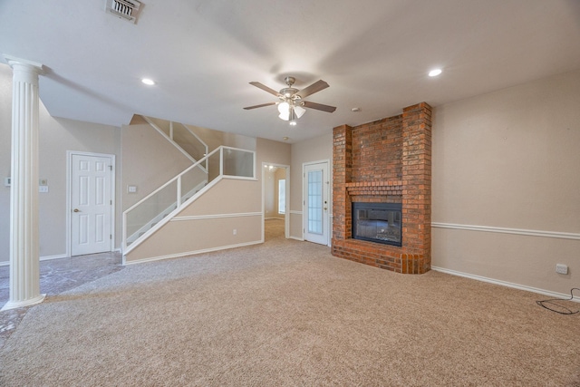 unfurnished living room with carpet flooring, ceiling fan, a fireplace, and decorative columns