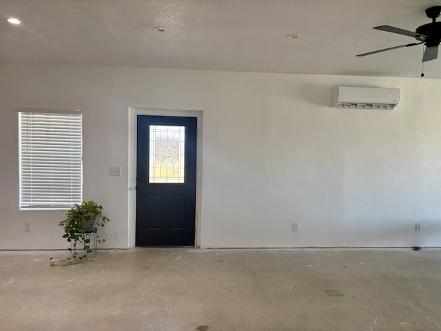 foyer entrance with an AC wall unit, ceiling fan, and concrete floors