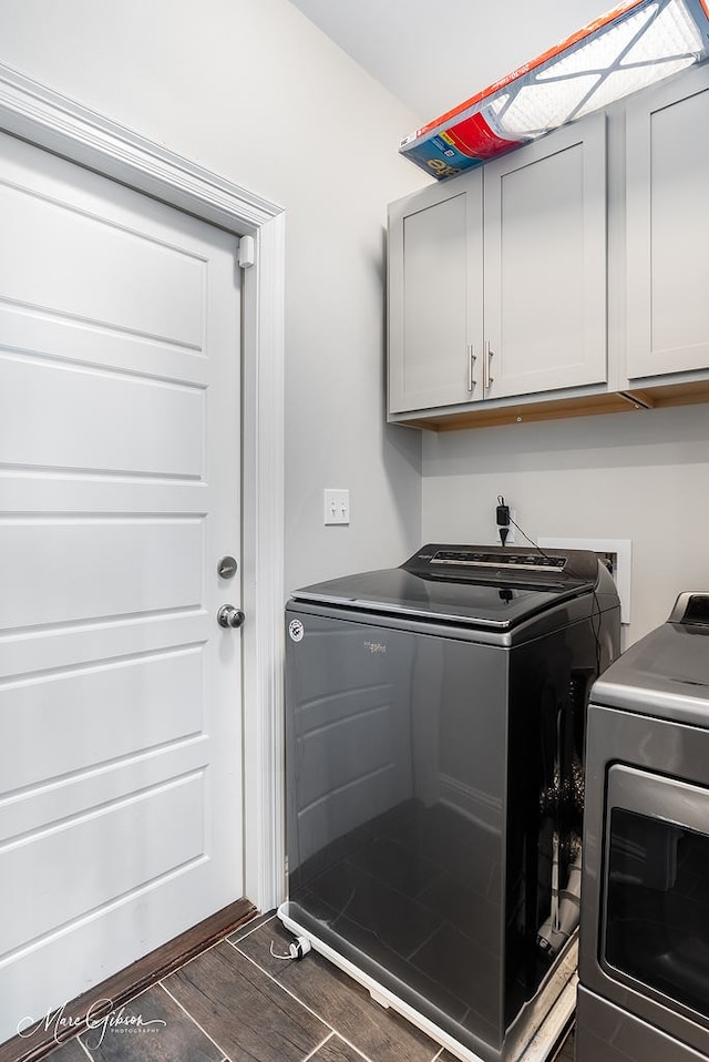 laundry area featuring cabinets, washing machine and dryer, and dark wood-type flooring