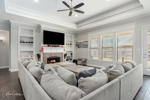 living room featuring a raised ceiling, ceiling fan, dark wood-type flooring, and crown molding