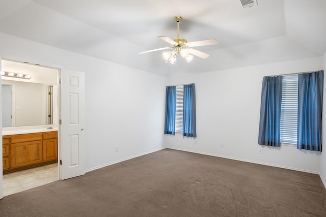 unfurnished bedroom with connected bathroom, light colored carpet, and ceiling fan