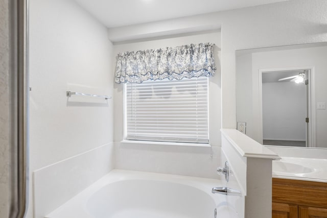 bathroom with vanity, a tub to relax in, and ceiling fan