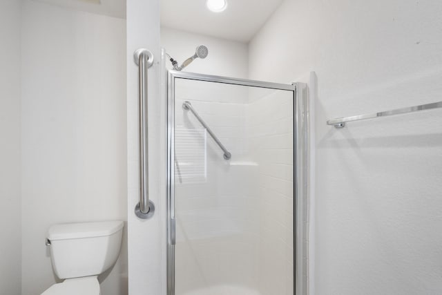 bathroom with toilet and a shower with shower door