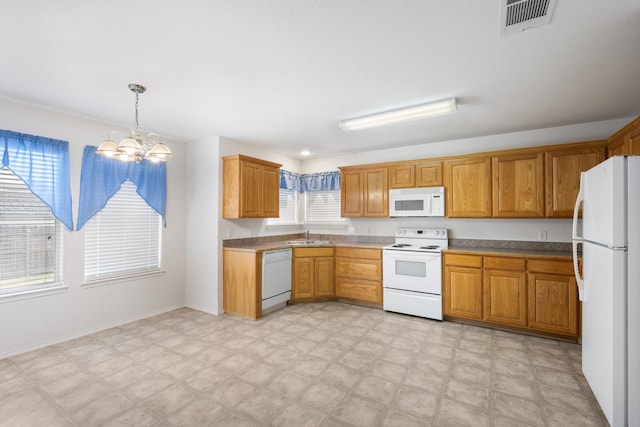 kitchen with a chandelier, pendant lighting, white appliances, and sink