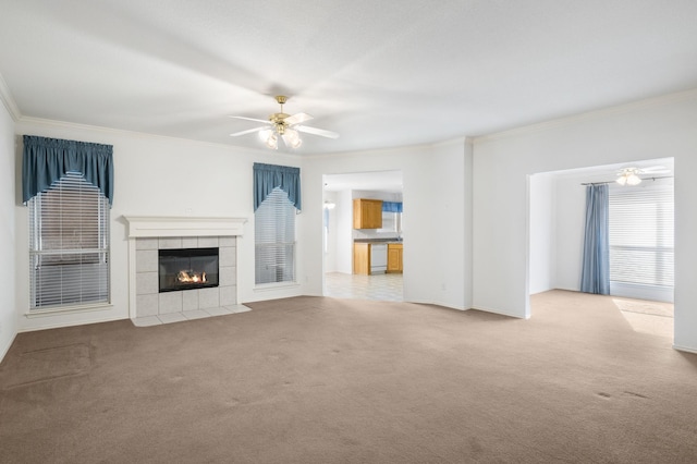 unfurnished living room with carpet flooring, ceiling fan, ornamental molding, and a tiled fireplace