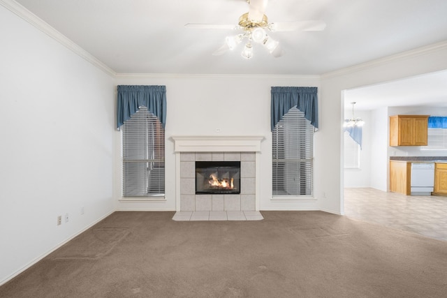 unfurnished living room featuring a tile fireplace, ornamental molding, ceiling fan with notable chandelier, and dark colored carpet