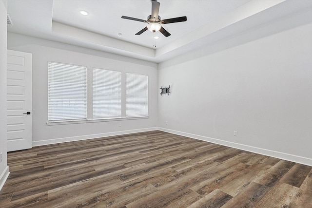 unfurnished room with dark hardwood / wood-style flooring, a raised ceiling, and ceiling fan