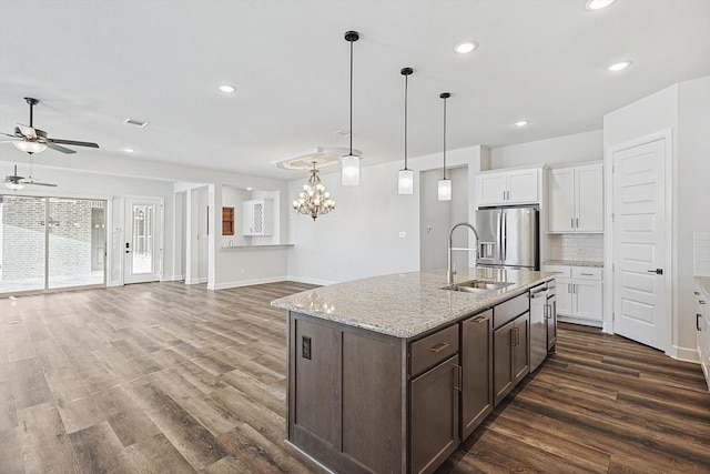 kitchen featuring sink, white cabinetry, stainless steel fridge, pendant lighting, and light stone countertops