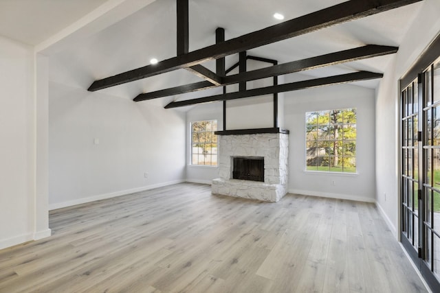 unfurnished living room with baseboards, a stone fireplace, lofted ceiling with beams, and wood finished floors