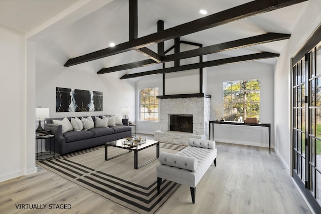 living area featuring lofted ceiling with beams, a stone fireplace, wood finished floors, and baseboards