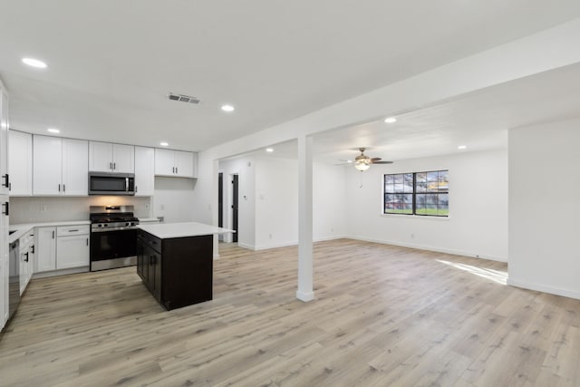 kitchen with white cabinetry, a center island, light wood-type flooring, ceiling fan, and stainless steel appliances