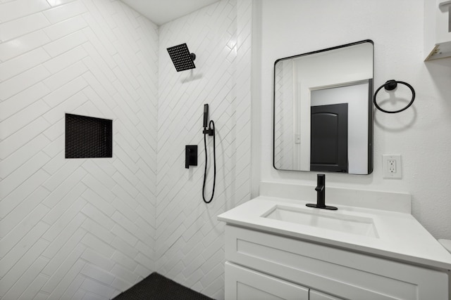 bathroom with tiled shower and vanity