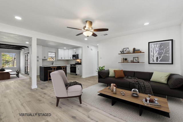 living area with light wood finished floors, visible vents, and recessed lighting