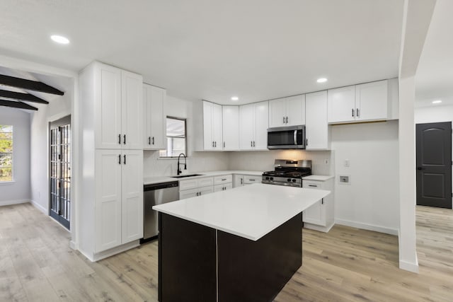 kitchen with light countertops, appliances with stainless steel finishes, a sink, and tasteful backsplash