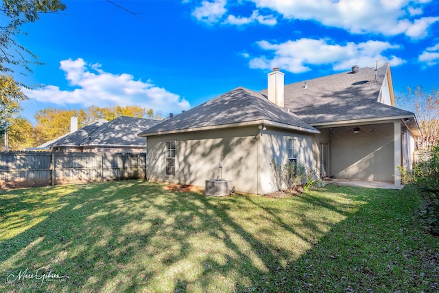 back of property featuring ceiling fan and a yard