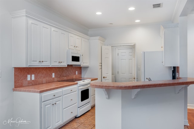 kitchen with a breakfast bar, white cabinets, and white appliances