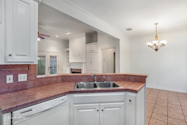 kitchen with sink, tile countertops, white dishwasher, pendant lighting, and white cabinets