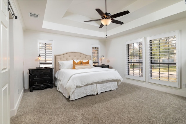 bedroom featuring a barn door, ceiling fan, a raised ceiling, and carpet floors