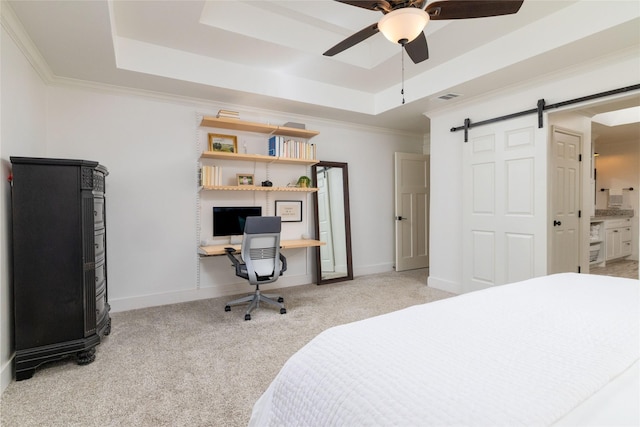 carpeted bedroom with ceiling fan, a raised ceiling, connected bathroom, and a barn door