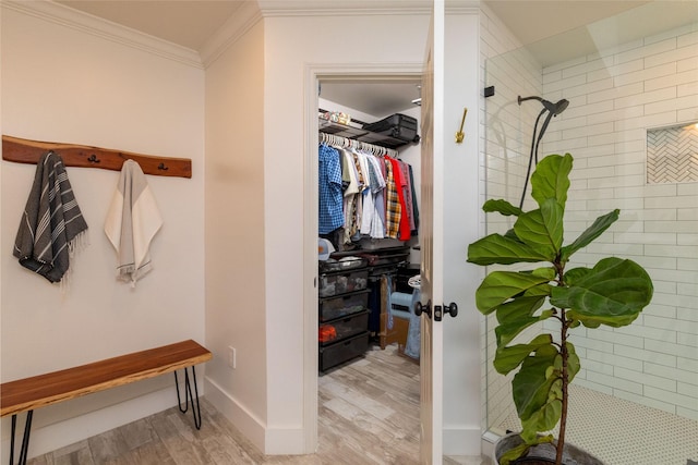 interior space with hardwood / wood-style flooring, ornamental molding, and a tile shower