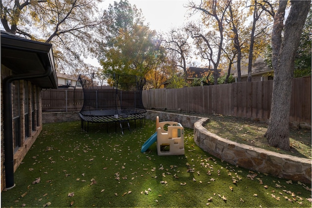 view of yard featuring a playground and a trampoline