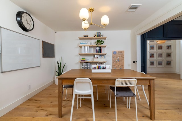 dining area featuring light wood-type flooring and a notable chandelier