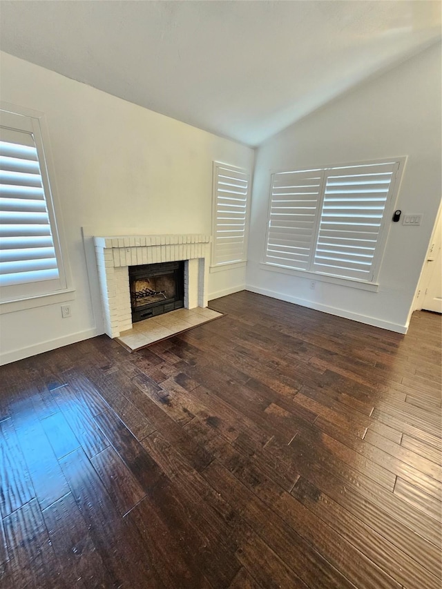 unfurnished living room featuring lofted ceiling, a brick fireplace, and dark hardwood / wood-style flooring