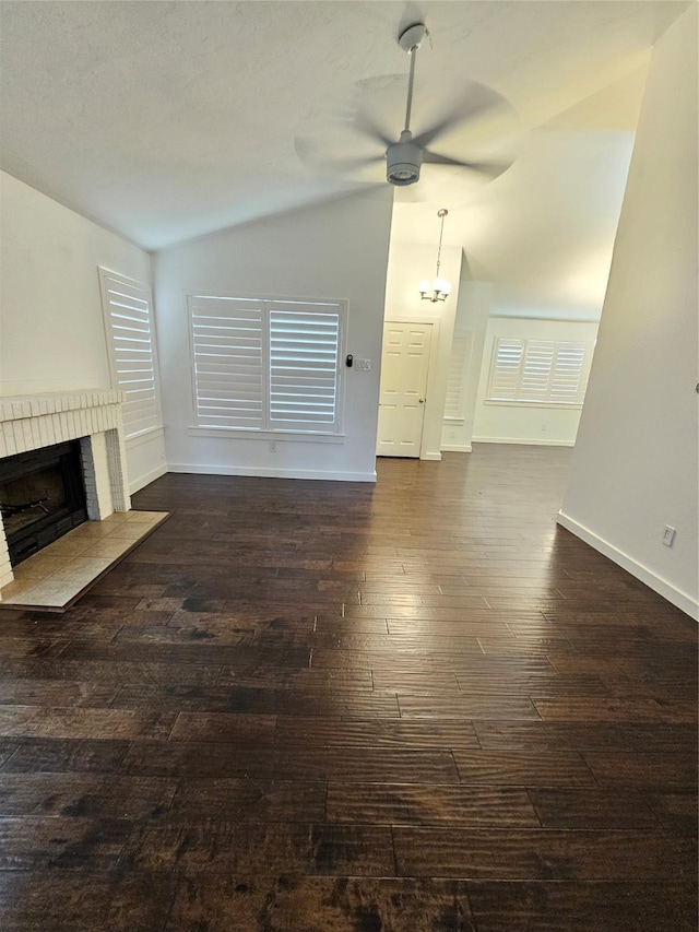 unfurnished living room featuring ceiling fan, lofted ceiling, dark hardwood / wood-style floors, and a brick fireplace