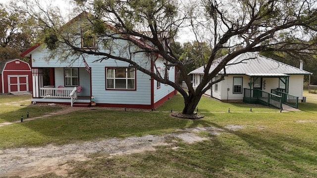 view of front of house featuring covered porch, a shed, and a front lawn