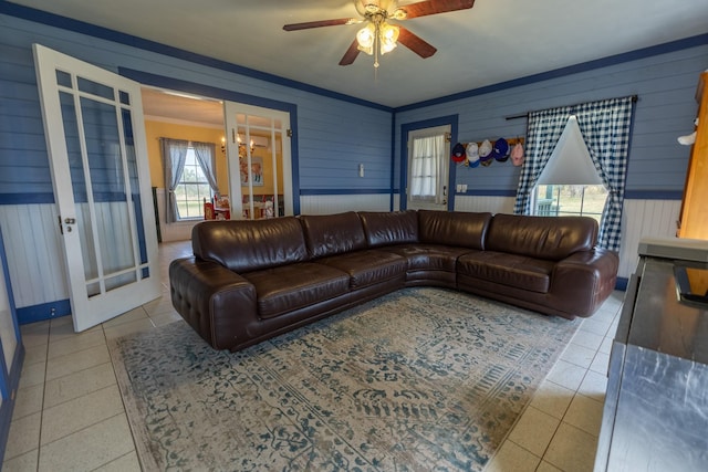 living room featuring ornamental molding, ceiling fan with notable chandelier, tile patterned floors, and french doors