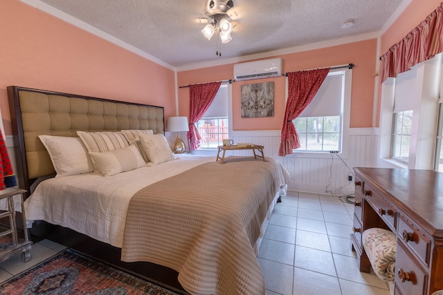 bedroom with ornamental molding, light tile patterned floors, a textured ceiling, and a wall unit AC