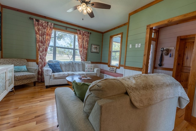 living room with crown molding, light hardwood / wood-style flooring, and ceiling fan