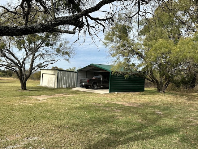 view of yard featuring an outbuilding, a carport, and a garage