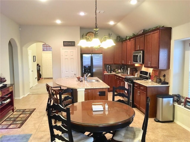 kitchen with an inviting chandelier, a center island with sink, hanging light fixtures, vaulted ceiling, and appliances with stainless steel finishes