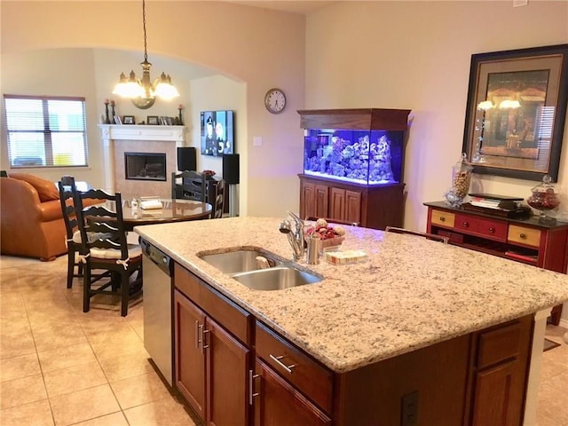 kitchen with a kitchen island with sink, sink, light tile patterned floors, an inviting chandelier, and dishwasher