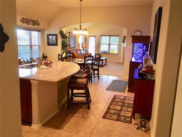 kitchen with sink, pendant lighting, vaulted ceiling, a breakfast bar, and light tile patterned flooring