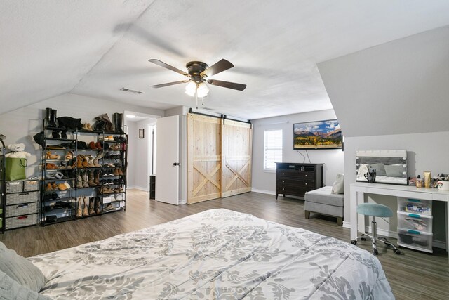 bedroom featuring vaulted ceiling, a barn door, ceiling fan, and dark hardwood / wood-style floors