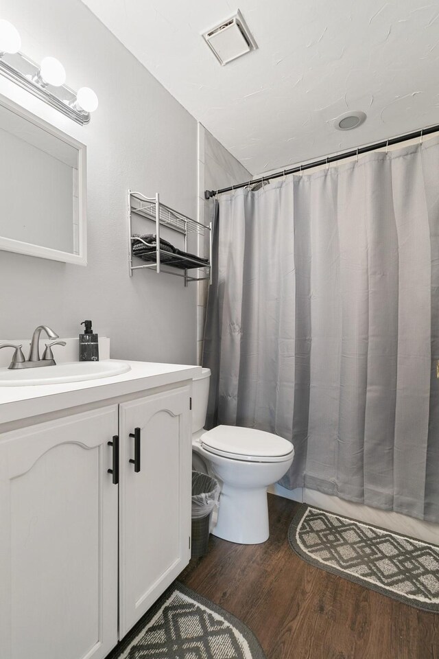 bathroom featuring hardwood / wood-style floors, vanity, toilet, and curtained shower