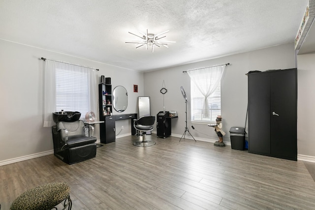 sitting room with ceiling fan, wood-type flooring, and a textured ceiling