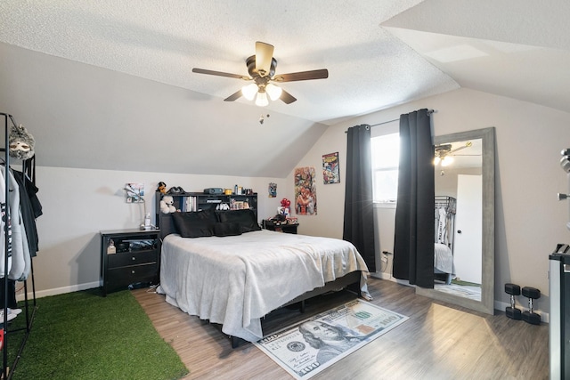 bedroom featuring wood-type flooring, a textured ceiling, ceiling fan, and lofted ceiling