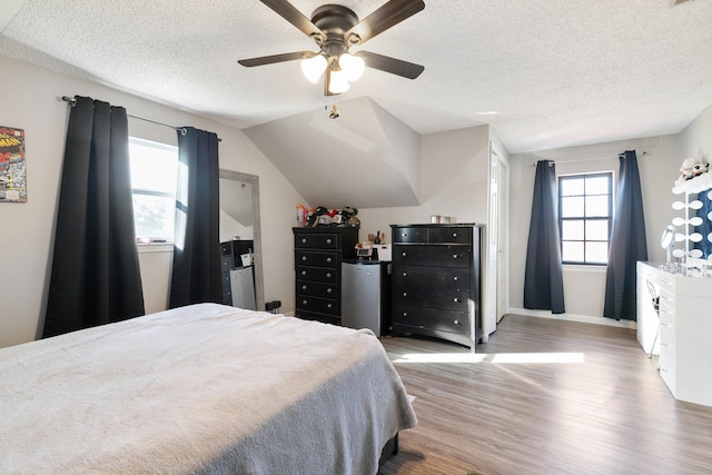 bedroom featuring ceiling fan, light wood-type flooring, a textured ceiling, and vaulted ceiling