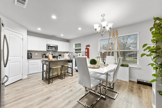 dining area featuring plenty of natural light, light hardwood / wood-style flooring, and an inviting chandelier